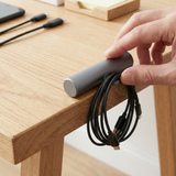 Mano colocando la base CableDock Pro de 11 centímetros en el borde de un escritorio
