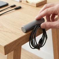 Mano colocando la base CableDock Pro de 11 centímetros en el borde de un escritorio