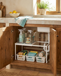 Mueble bajo fregadero abierto y ordenado con el estante UnderSink Flex y productos de limpieza