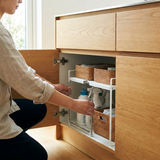 Persona ajustando con las manos el ancho extensible del estante UnderSink Flex dentro del mueble