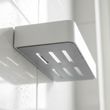Detalle del soporte adhesivo y las ranuras de drenaje del estante ShowerGrip Corner