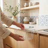 Manos colgando la cesta DoorRack Slim sobre la puerta de un armario de cocina